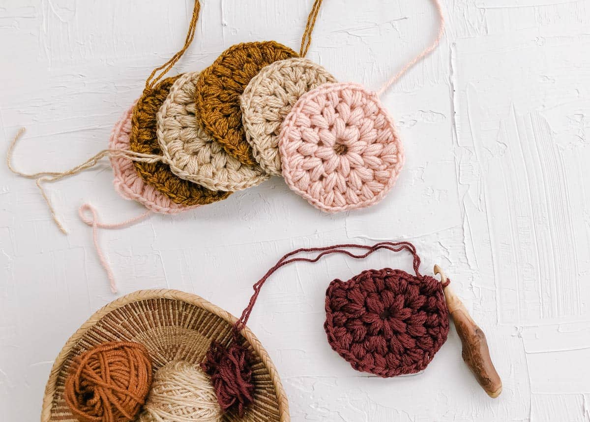 Crochet puff stitch circles made from scrap yarn. Also pictured a hand carved wooden crochet hook.