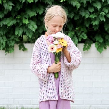 A young child wearing a casual crochet cardigan made with hand dyed yarn.