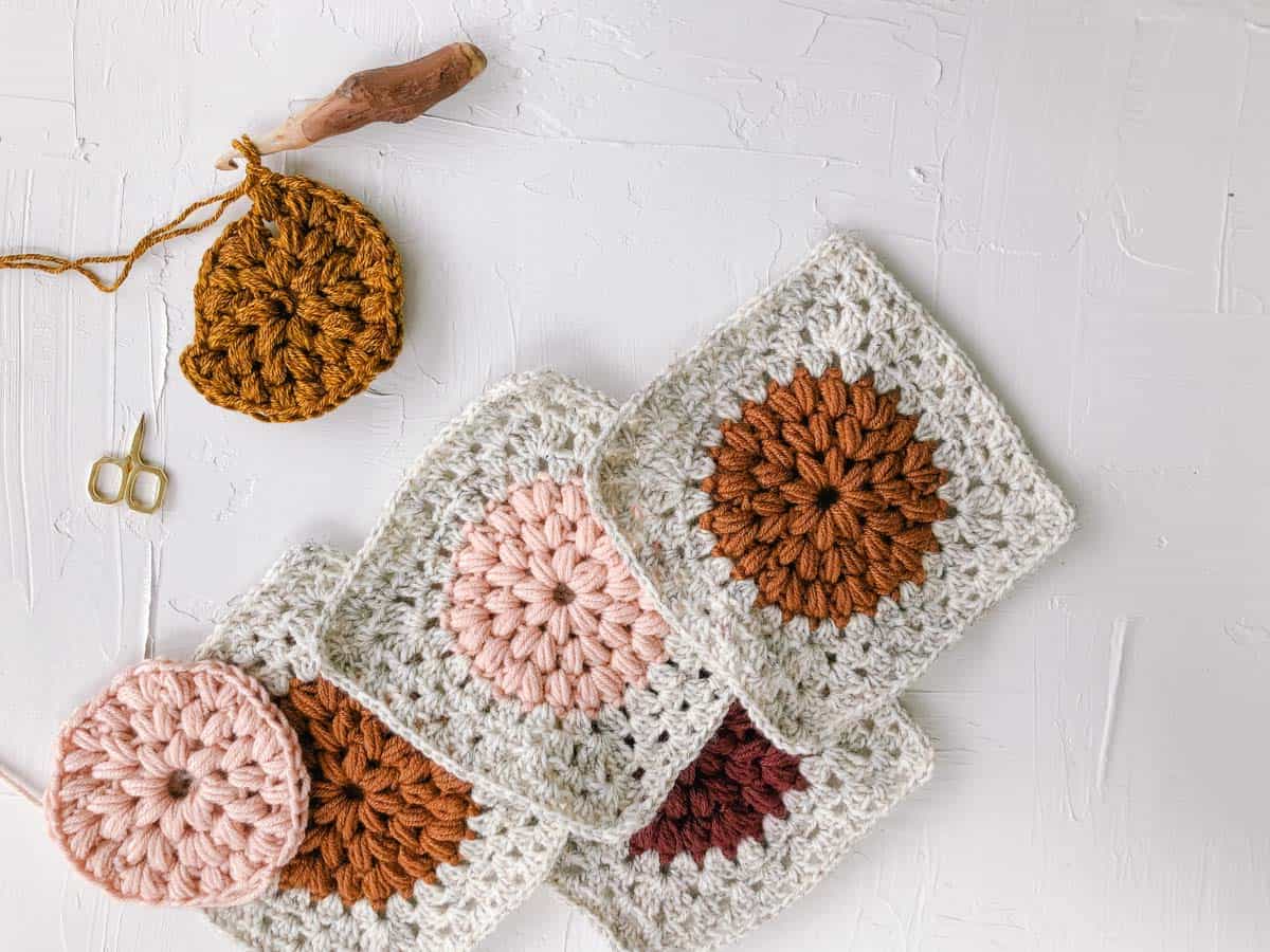 Modern crochet granny squares with puff stitch centers made in a variety of warm oranges and pinks.
