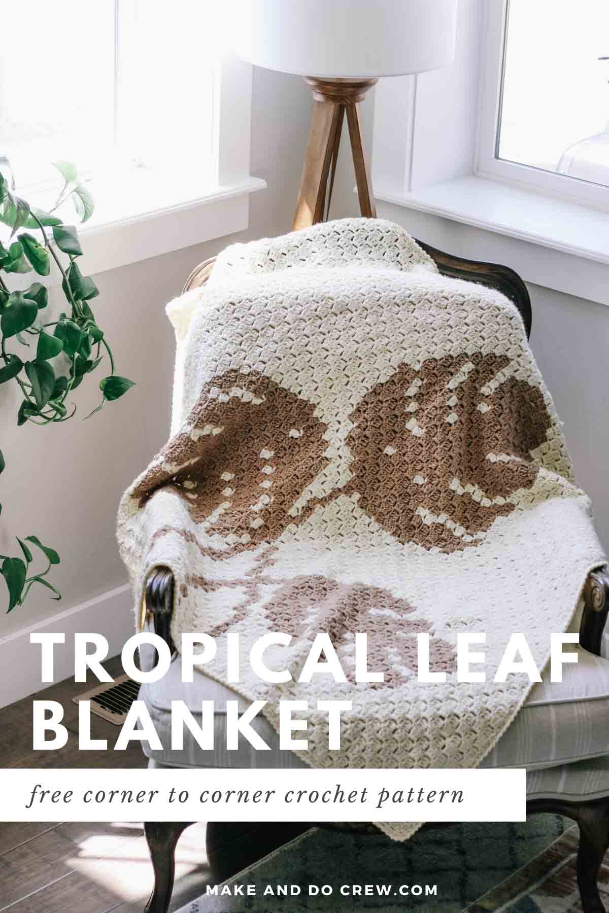 A monstera leaf corner to corner crochet blanket draped over a modern chair in a sunroom.