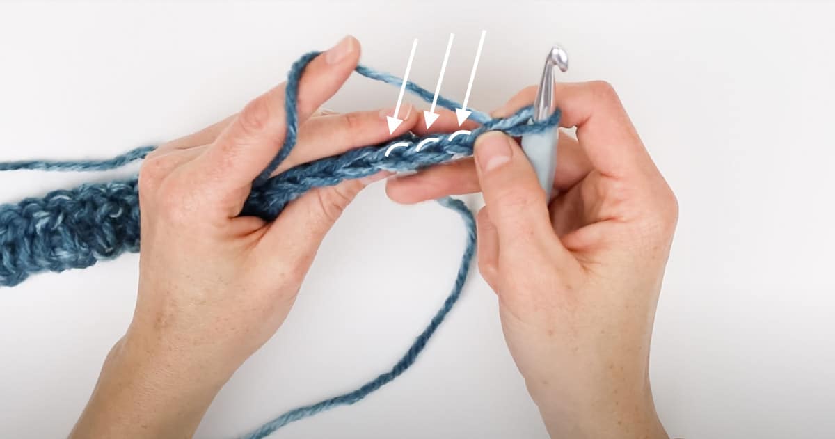 A row of crocheting with arrows pointing to the back loop of each crochet stitch "V" shape.