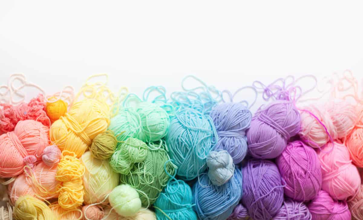 A haphazard row of yarn balls arranged in a color gradient.