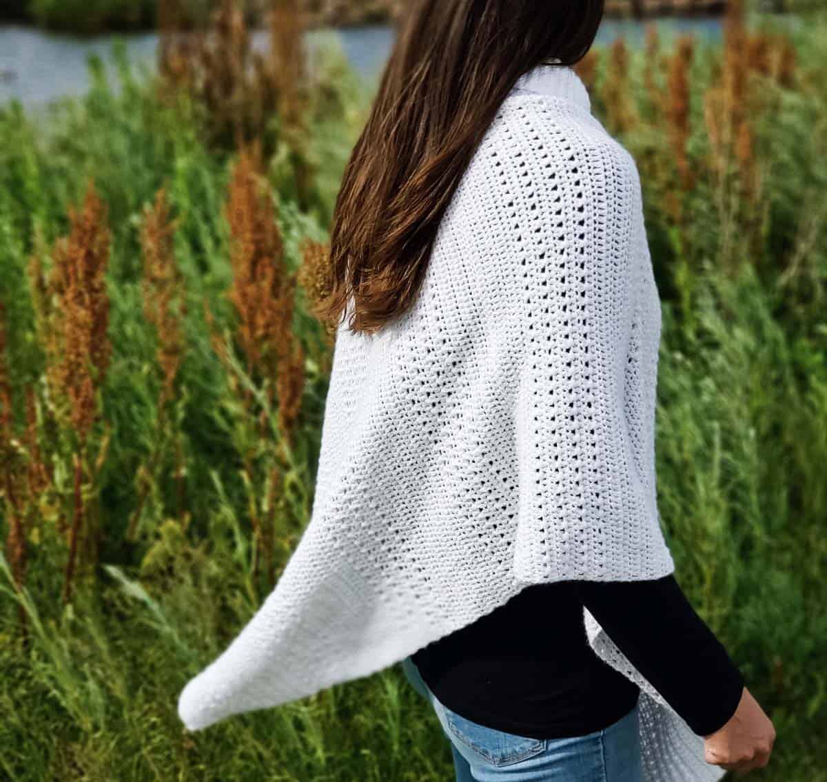 Shot from behind: a woman wearing a crochet poncho made from a rectangle.