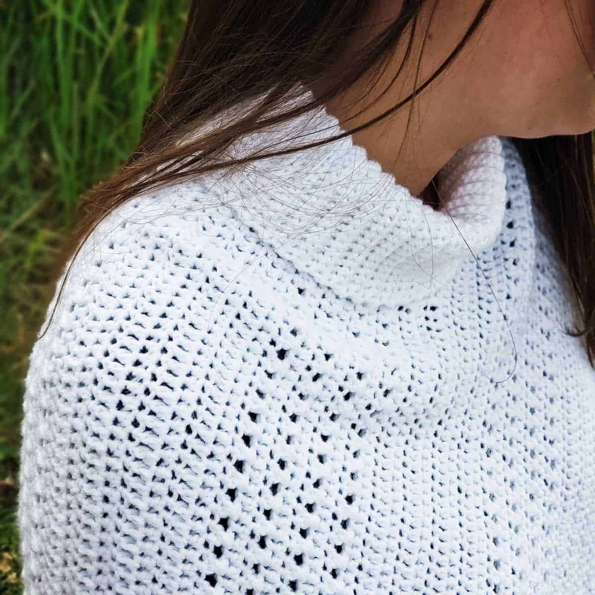 A close up of a woman wearing a crochet poncho made from a rectangle.