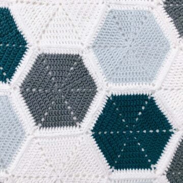 An overhead view of a crochet hexagon blanket that uses a join as you go method to piece the hexagons together.
