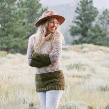 Woman standing in the mountains wearing a crochet yoke sweater pullover.