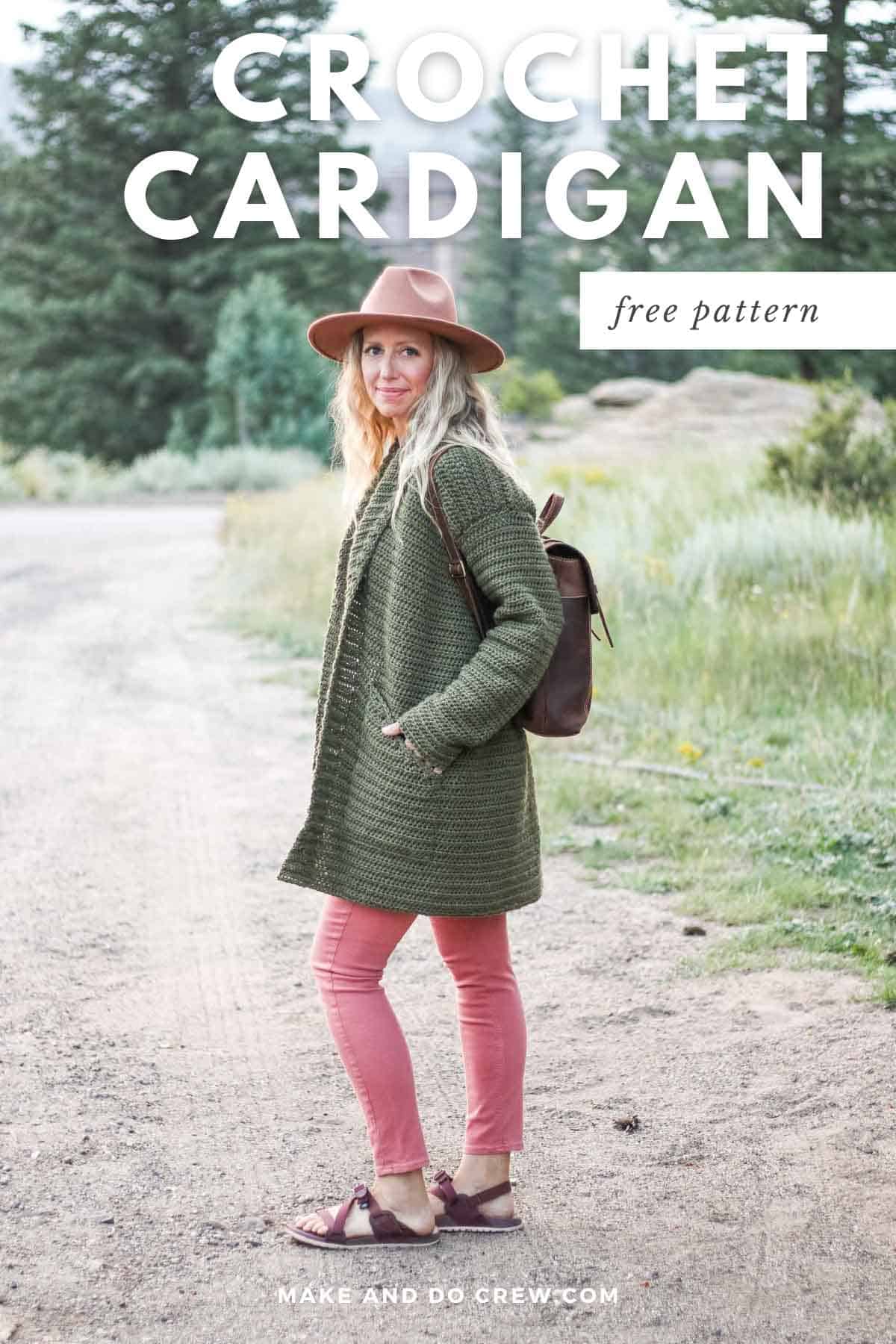A woman wearing a fedora hat, an olive green crochet sweater with her hands in the pockets, and a brown leather backpack.