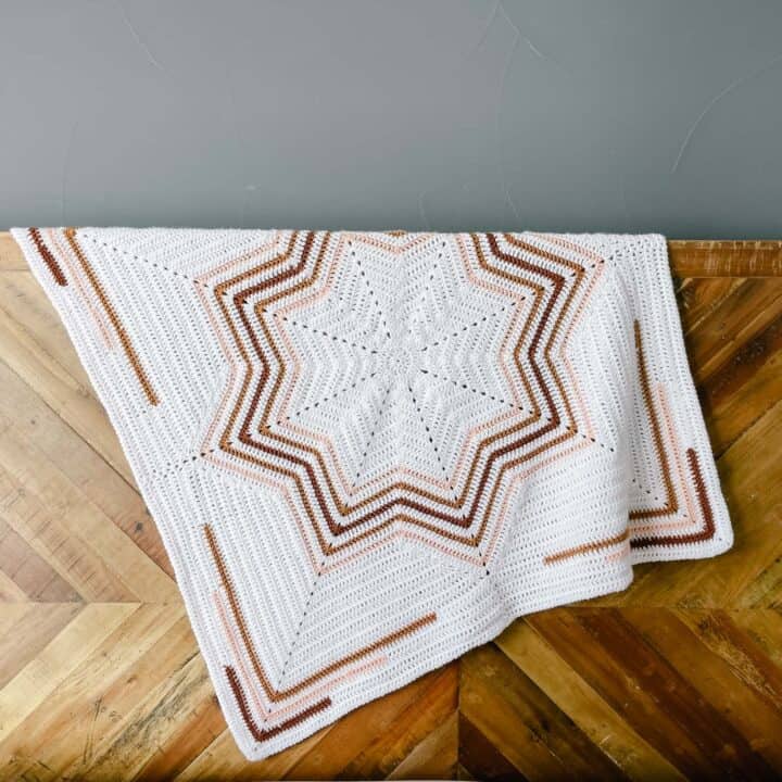 A crochet 8 point star blanket draped over a wooden bed.
