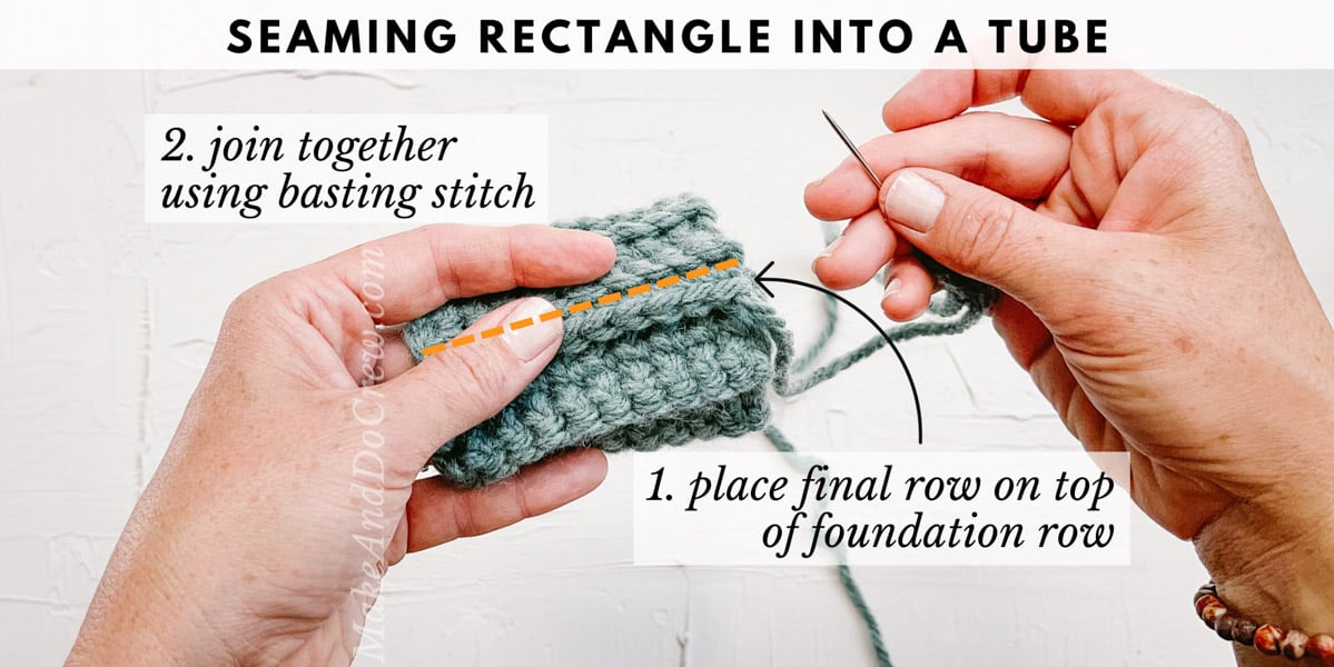 A woman's hands holding a tapestry needle and a crochet rectangle folded into a tube shape.