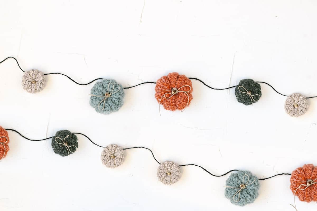 A series of rustic crochet pumpkins tied to a strand of jute to create an autumn garland.