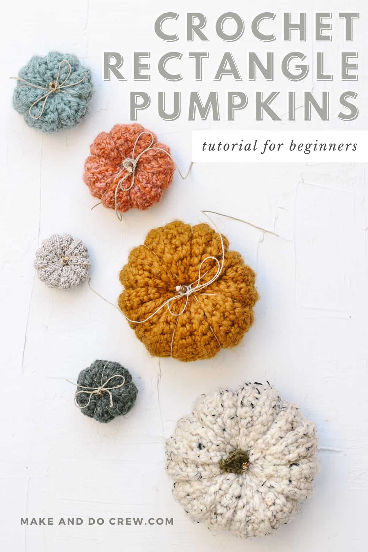 An overhead view of small, medium and large crochet pumpkins with jute tied around the stems.