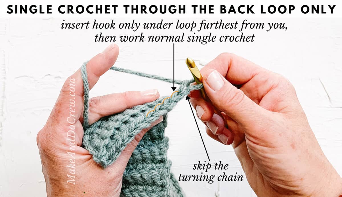 A closeup of women's hands holding a blue crochet swatch and a crochet hook to demonstrate how to crochet through back loop only.