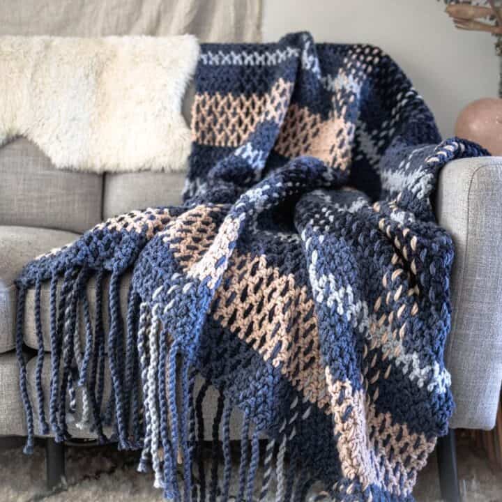 A plaid blanket with basic stripes draped on a couch.