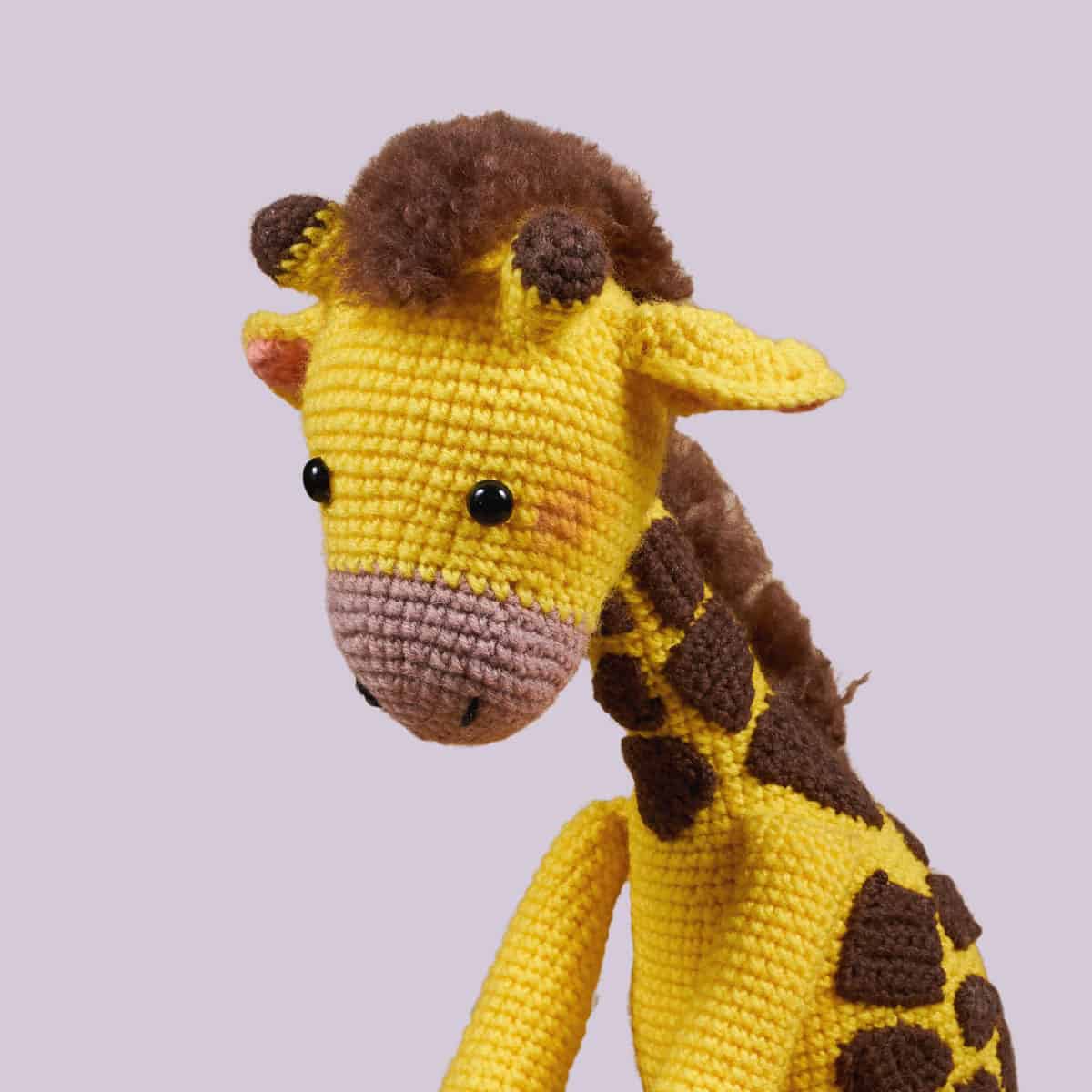 Close-up shot of a crochet giraffe amigurumi doll on a white background.