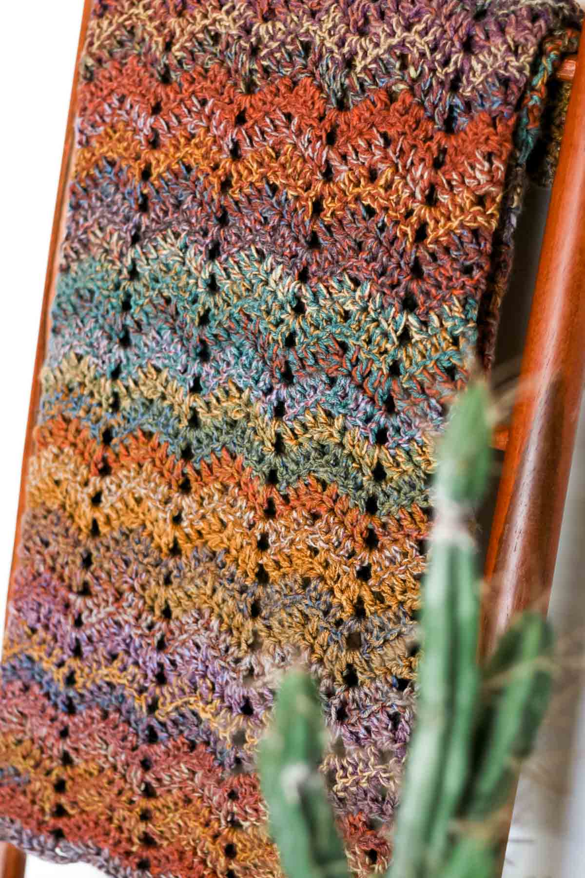 A crochet blanket folded on a ladder.
