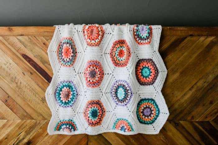 A hexagon crochet flower blanket draped on a wooden table.