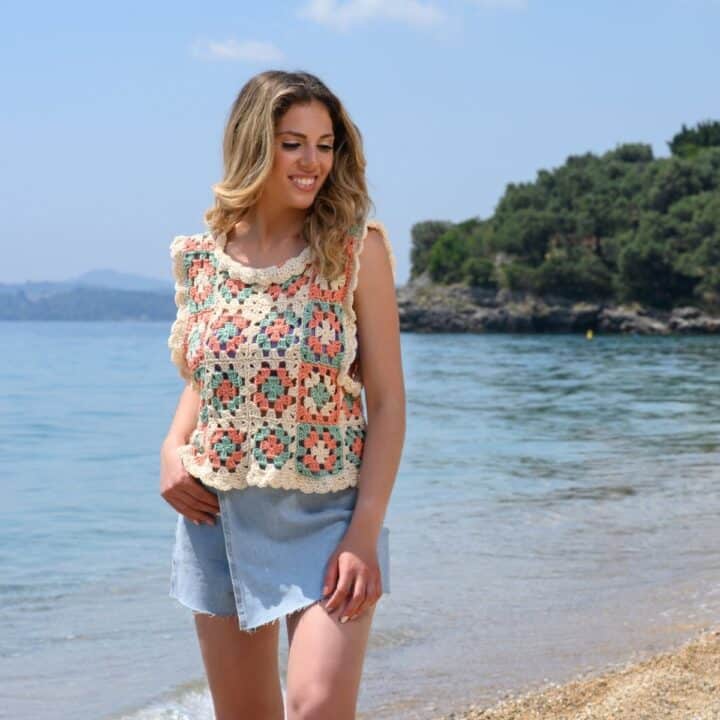 A woman by the beach wearing a sleeveless crochet granny square top.