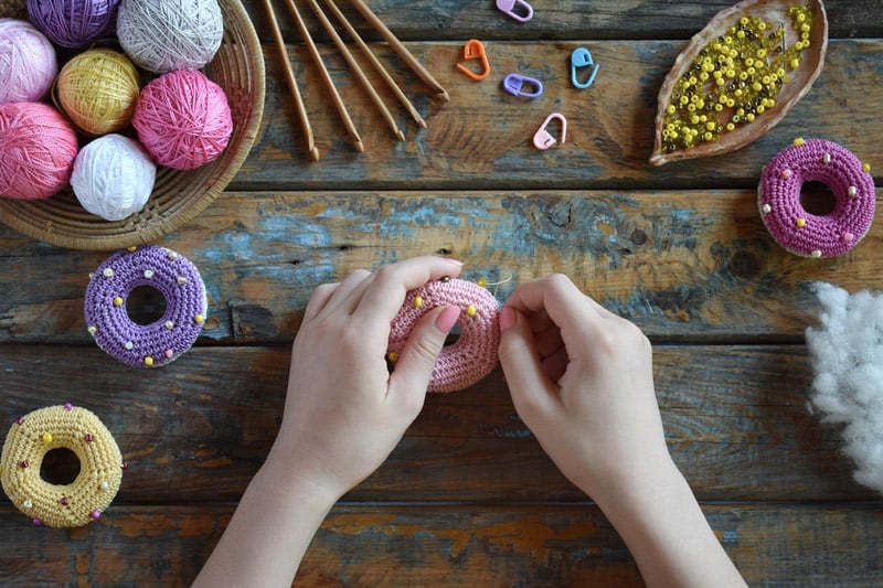 Woman's hands working on a crochet donut amigurumi.