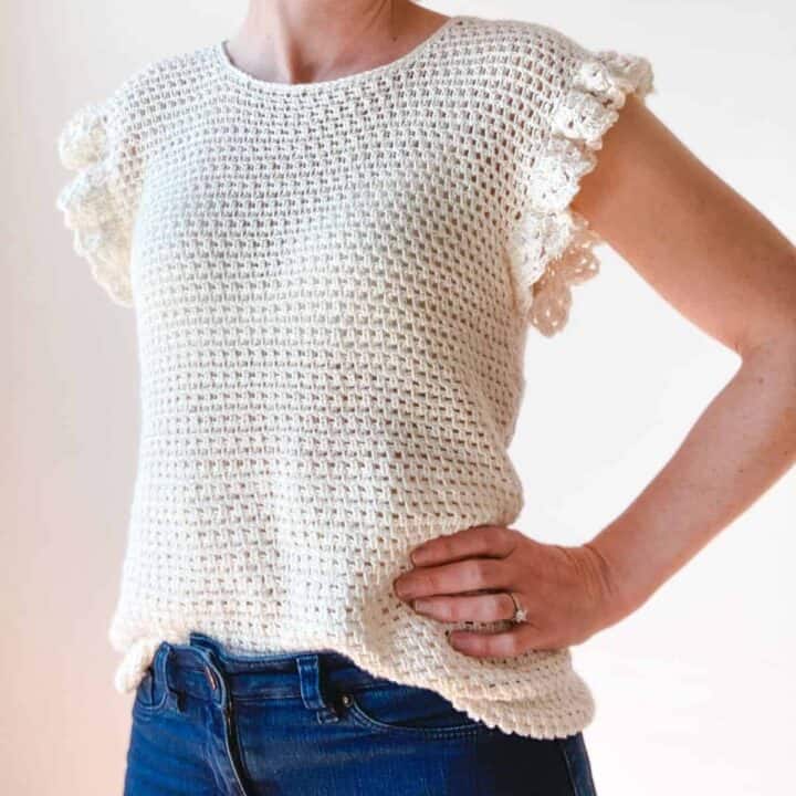 A woman wearing a ruffle sleeve crochet top.
