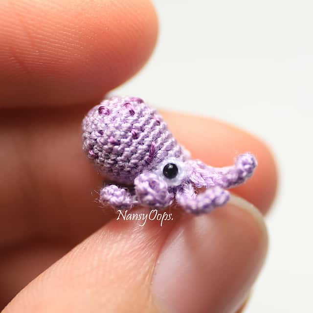 A hand holding a tiny purple octopus toy.
