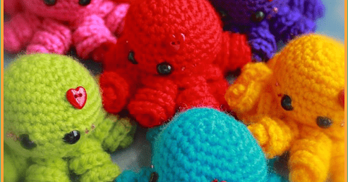 6 different colored crochet octopus amigurumi with red heart buttons.
