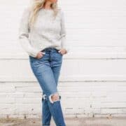 Woman wearing blue jeans and a crochet crew neck sweater.