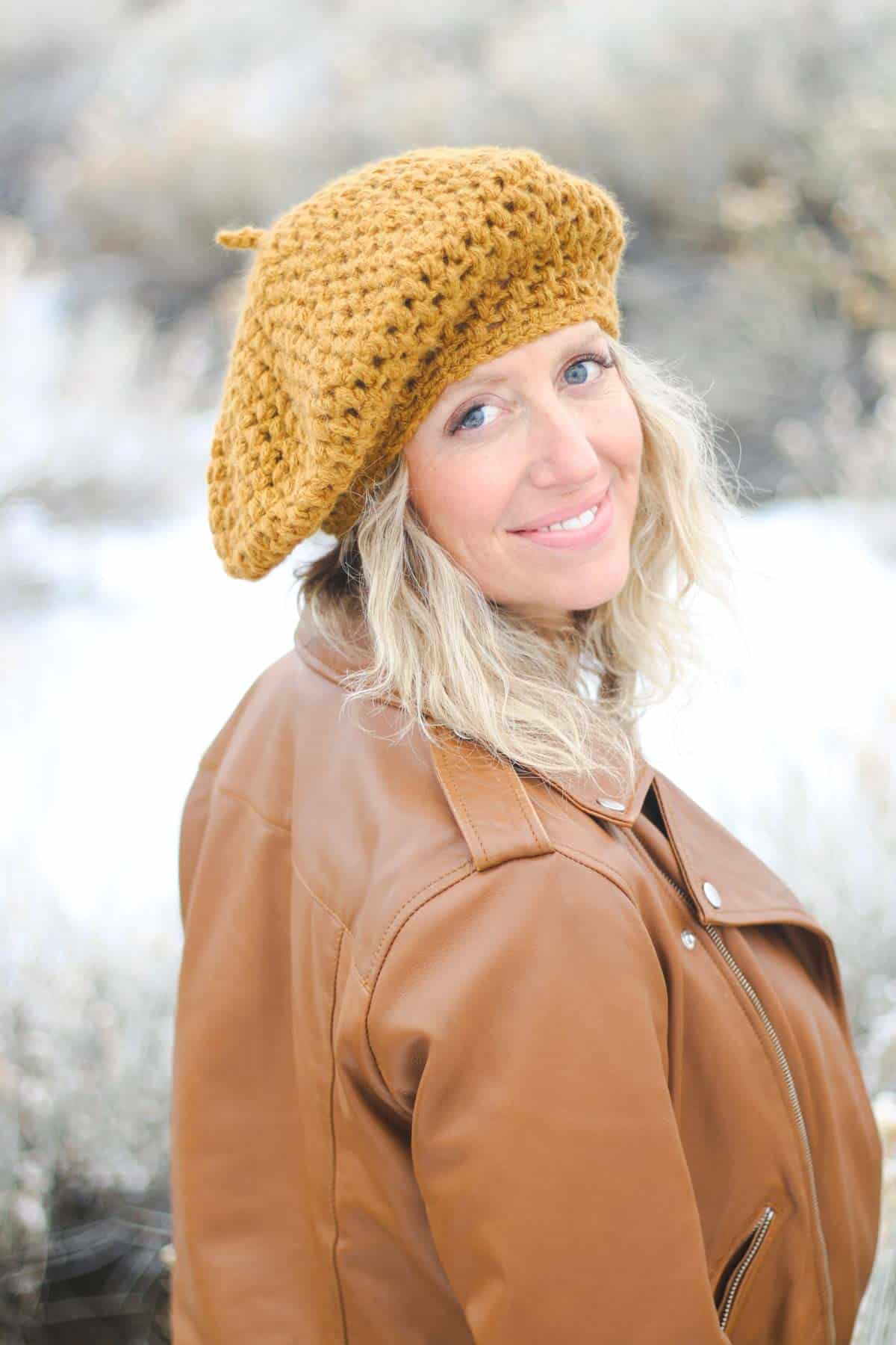 A woman smiling while wearing a slouchy beret hat.
