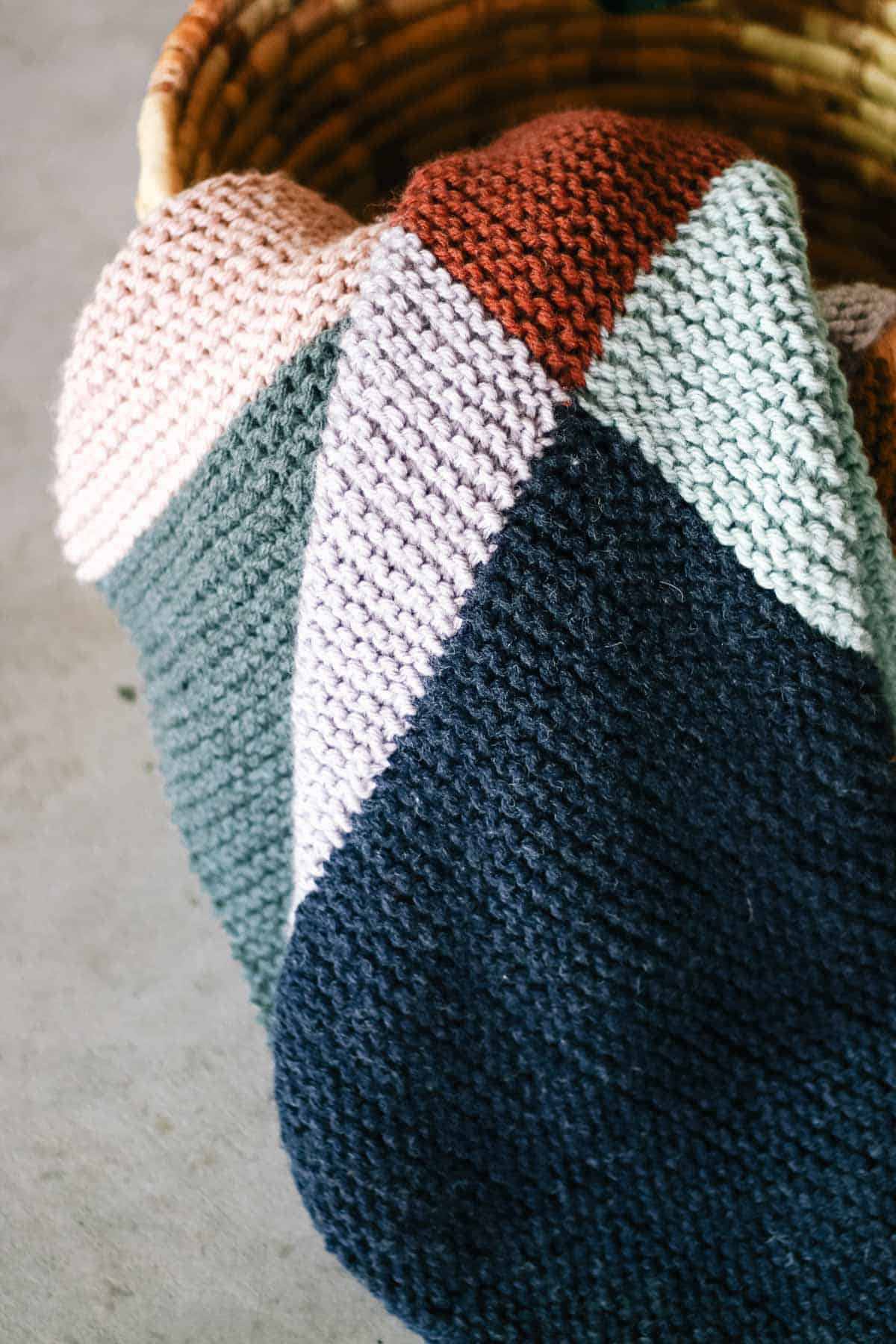Garter stitch knit blanket draped in a basket.