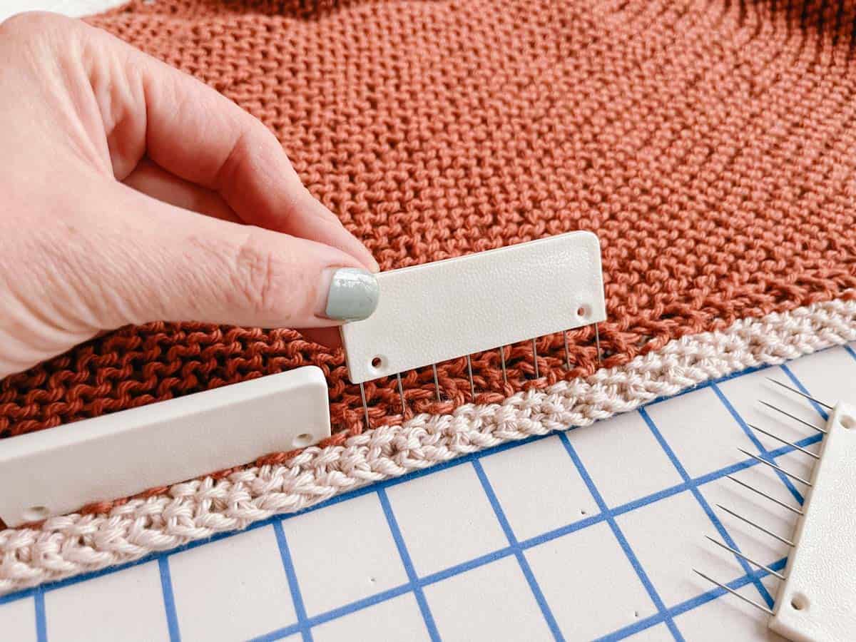 Knit blocking comb being pressed into the edge of a shawl during blocking process.