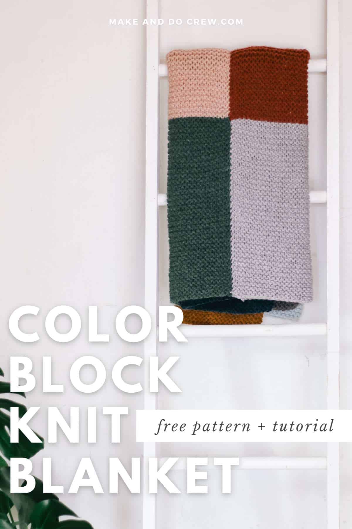 A color block knit blanket hanging on a white ladder.