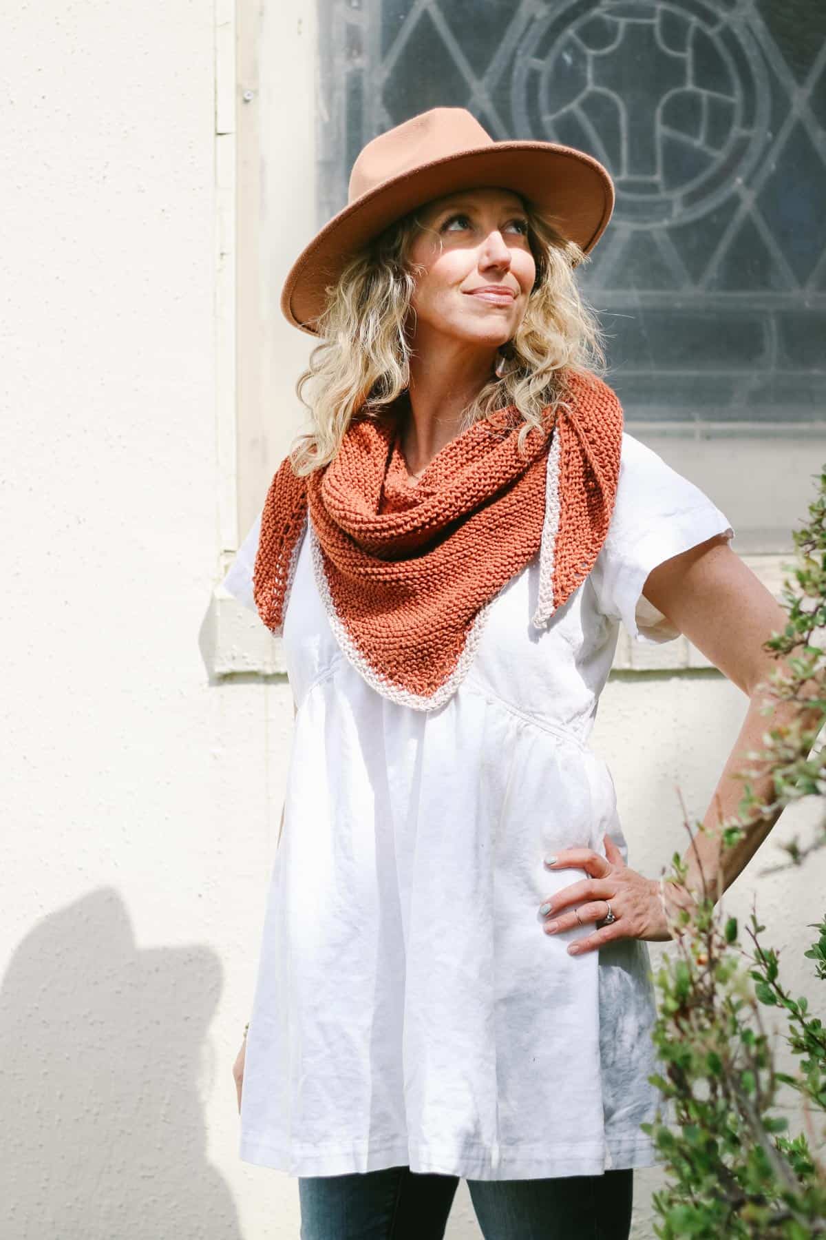 Woman standing in sun wearing a cotton knit triangle scarf.