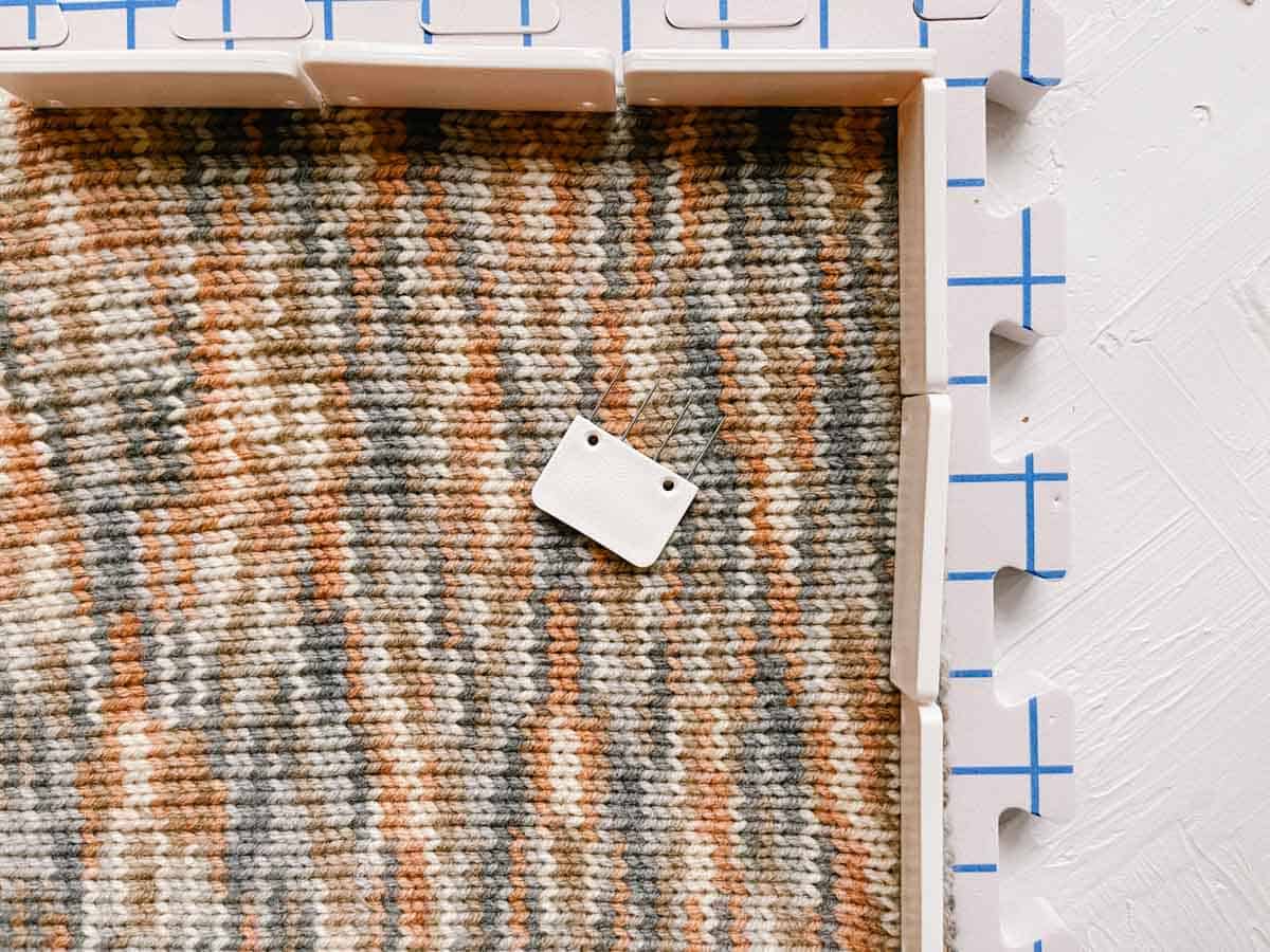 Stockinette knit fabric pinned to a foam mat with blocking pins.