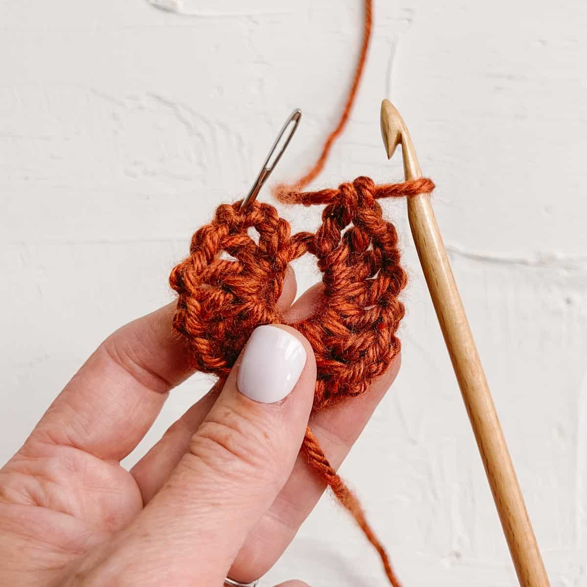 A circle of double crochet stitches made in burnt orange yarn.