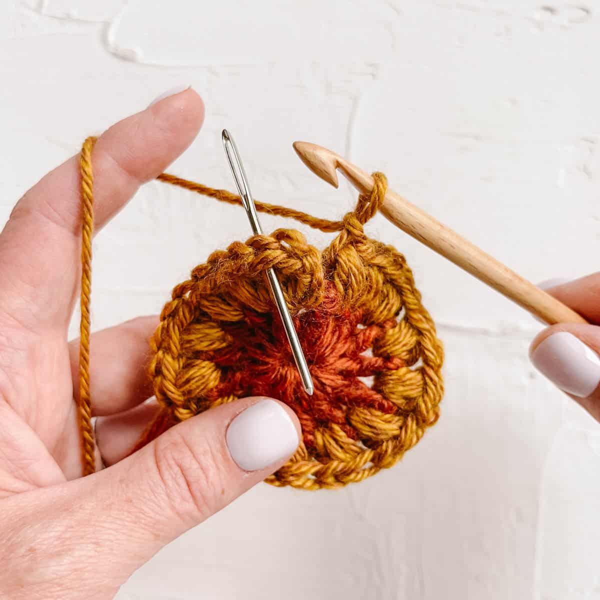 The inner circle of a crochet sunflower granny square made with puff stitches.