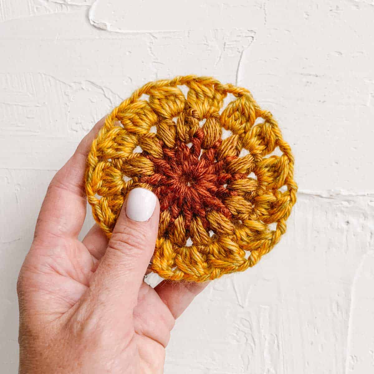 A crochet sunflower circle made with orange and yellow yarn.