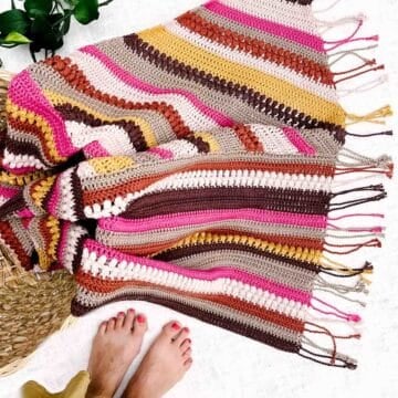 Crochet patchwork blanket on the floor with bare feet standing nearby.