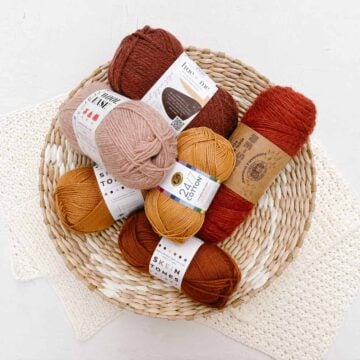 A basket of orange and pink skeins of yarn from Lion Brand.