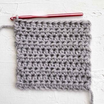 Swatch of half double crochet stitches (hdc) with a red crochet hook.