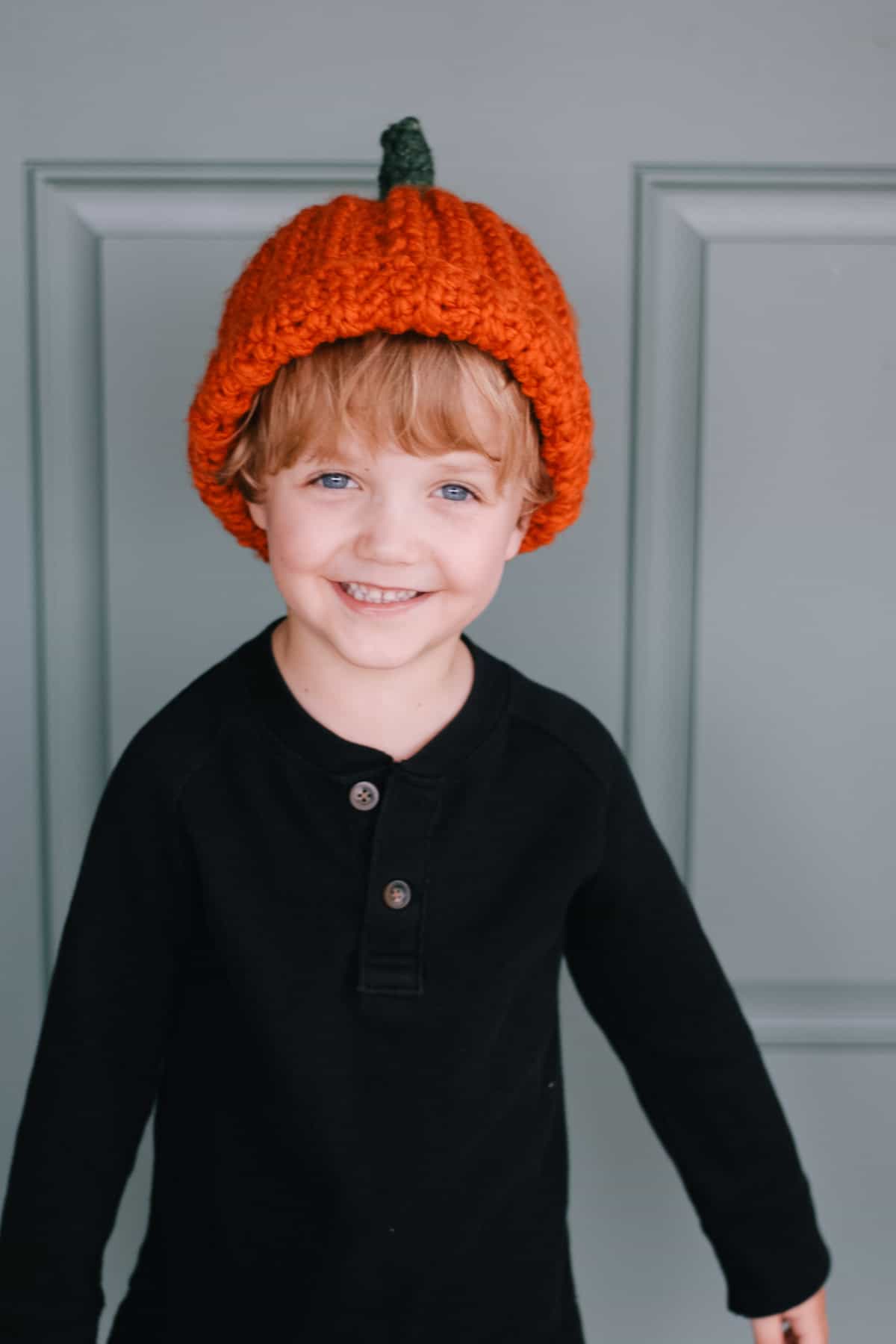Young child wearing a pumpkin crochet hat.