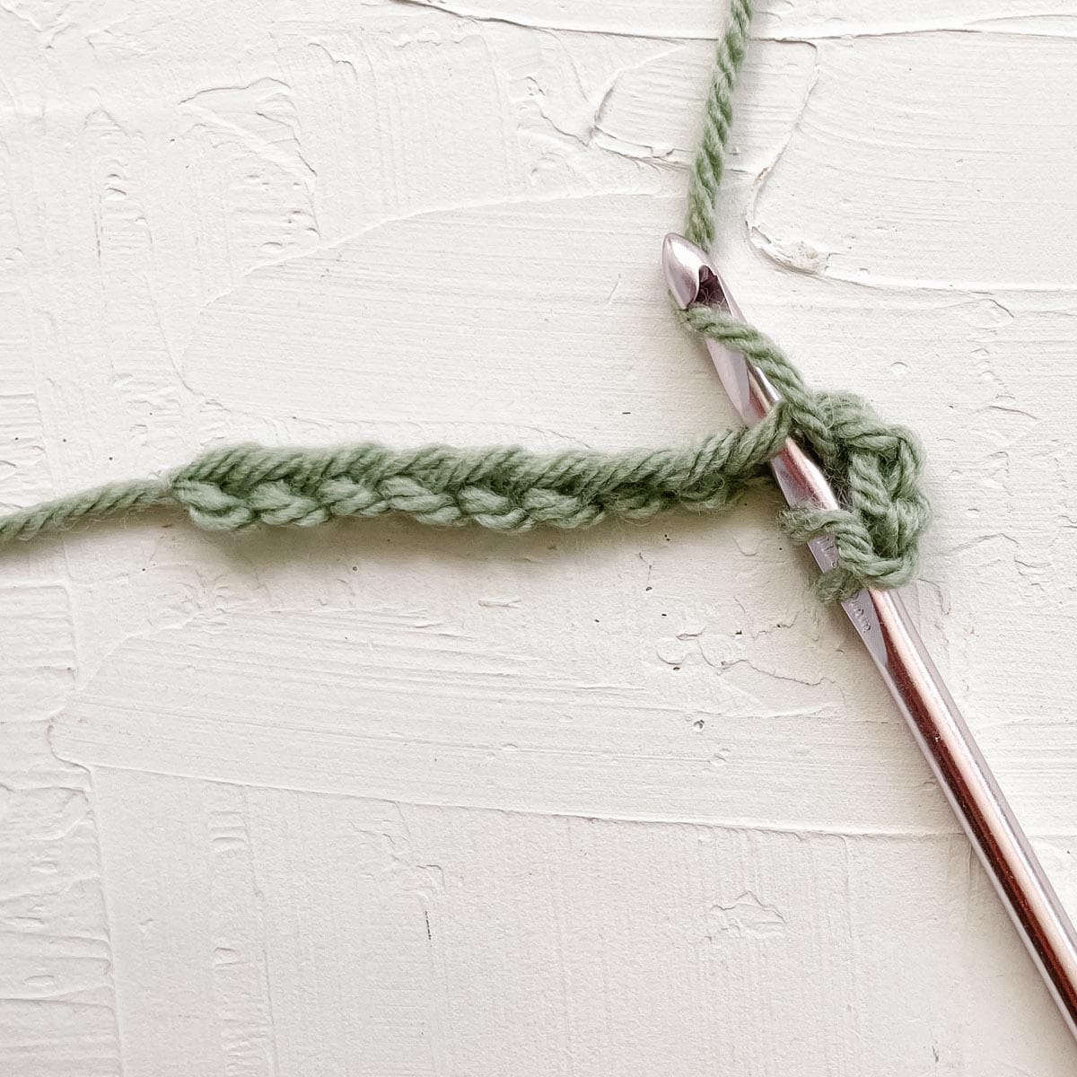 Step one of double crocheting: Yarn over and insert hook into fourth chain from the hook.