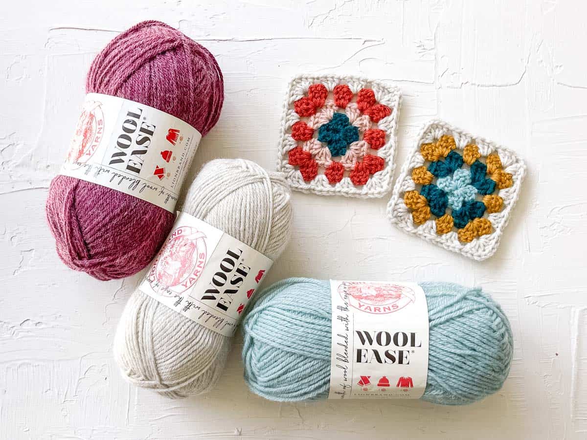 Lion Brand Wool-Ease yarn balls next to crochet granny squares.
