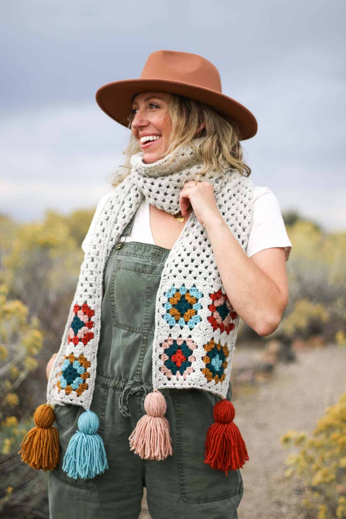 Granny square scarf with tassels modeled by a woman in the desert.