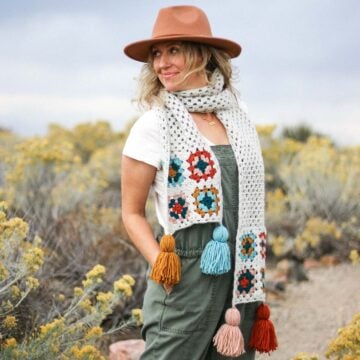 Granny square scarf modeled by a woman standing outside.