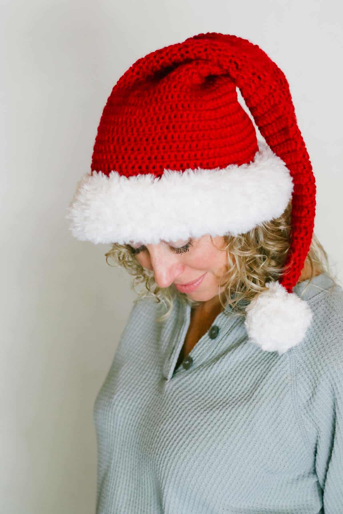 Adult woman wearing a crocheted Santa hat with a fur brim.