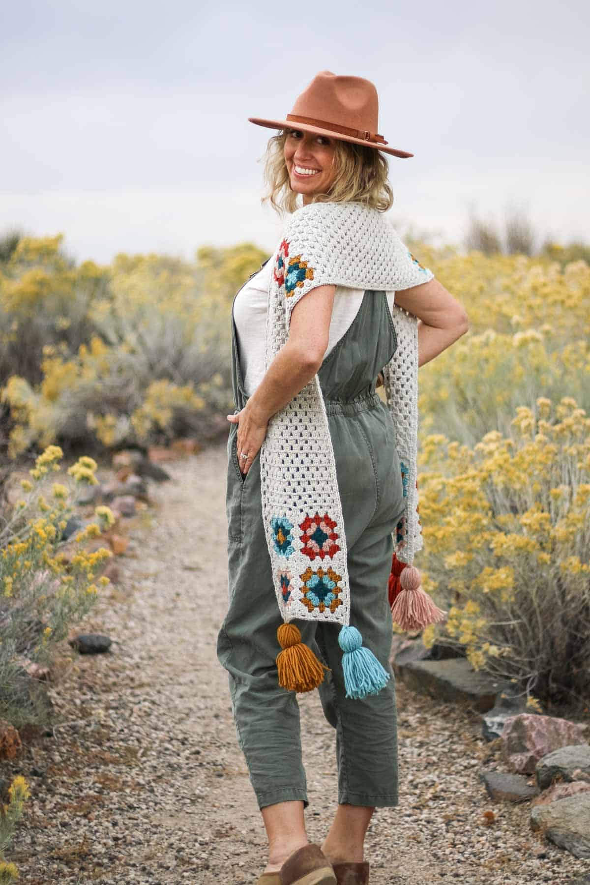 Crochet granny square scarf with tassels being modeled by a woman outdoors.
