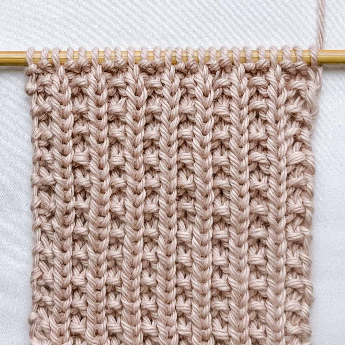 Knit ribbing stitch on a wooden knitting needle.