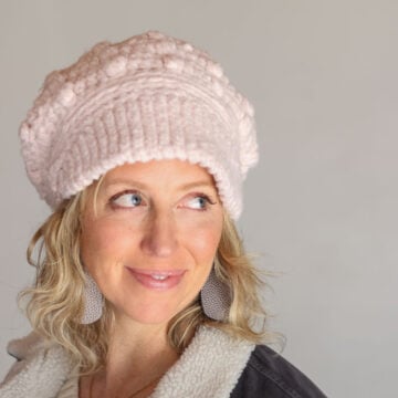 Crocheted newsboy hat with ribbed brim worn by blonde woman.