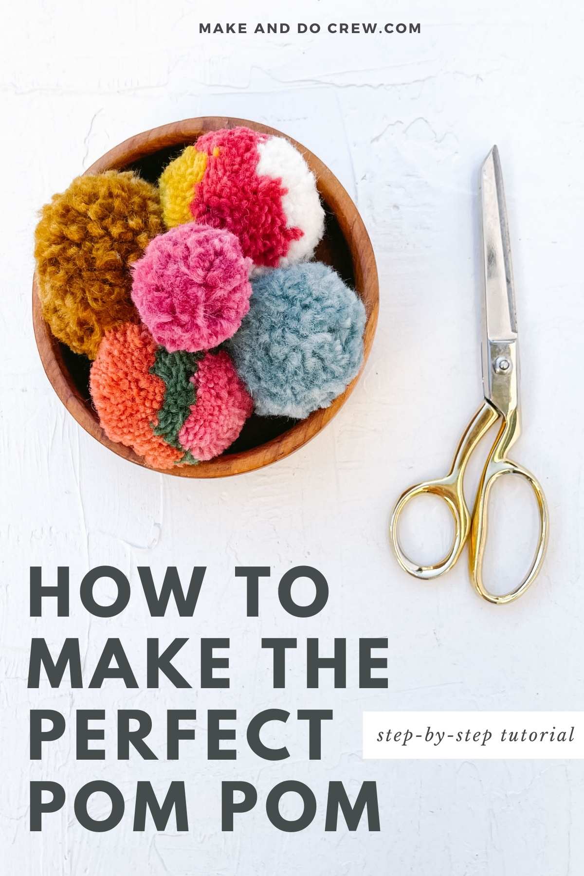A wooden bowl of perfect pom poms and a scissors.