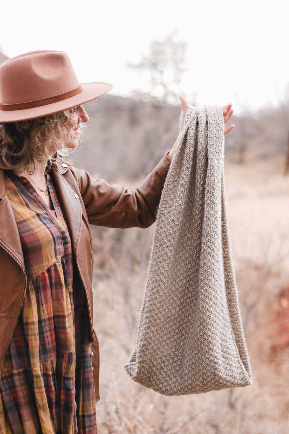 Simple knit eternity scarf draped over the hand of a woman in nature.