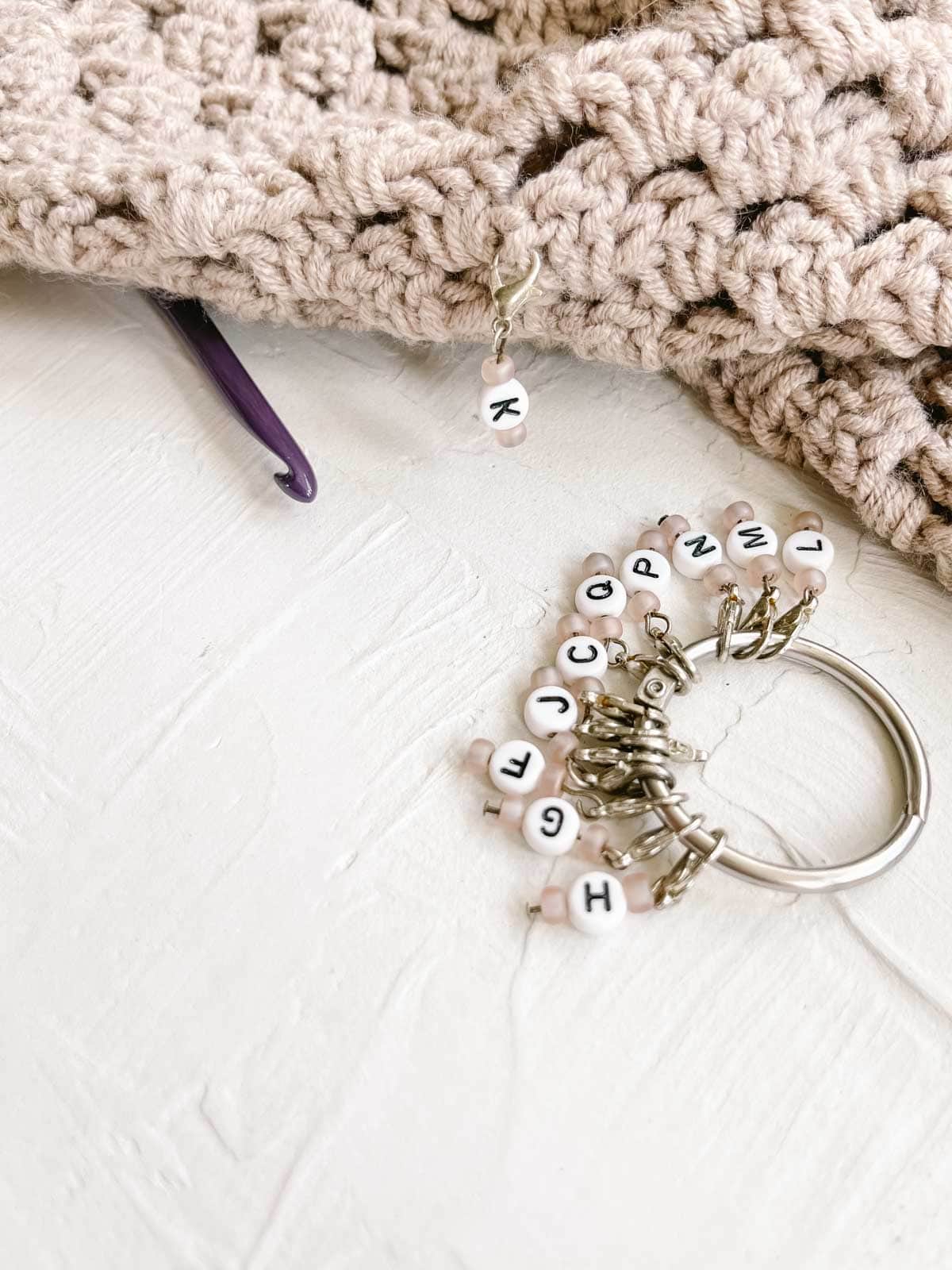 DIY personalized crochet stitch marker made from a keychain and craft beads with letters.